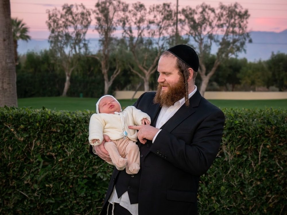 Rabbi Shlome Ekstein holding a newborn